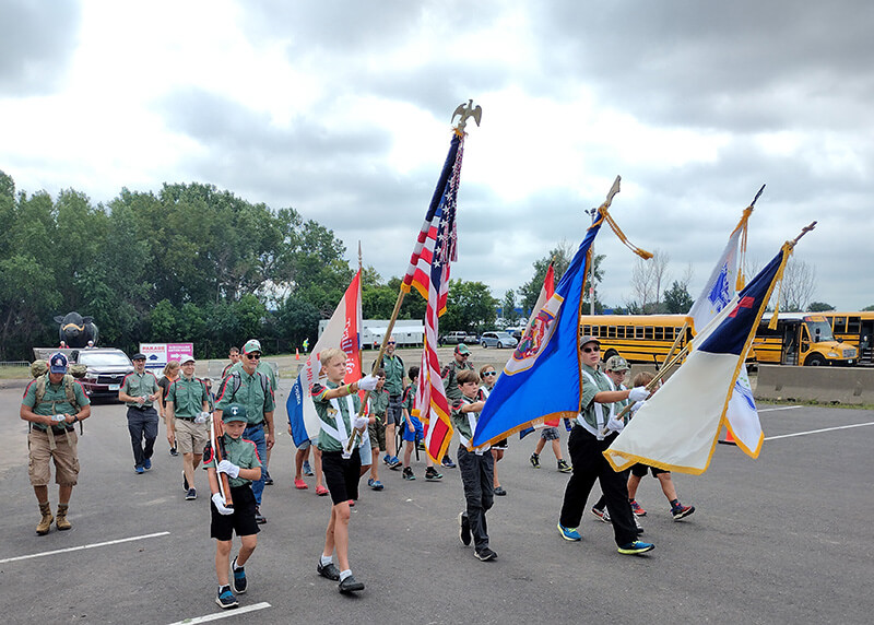 Trail Life troop boys at the MN state fair parade holding the American flag, Minnesota flag, Christian flag and Why Men and boys need to be involved in local and national politics